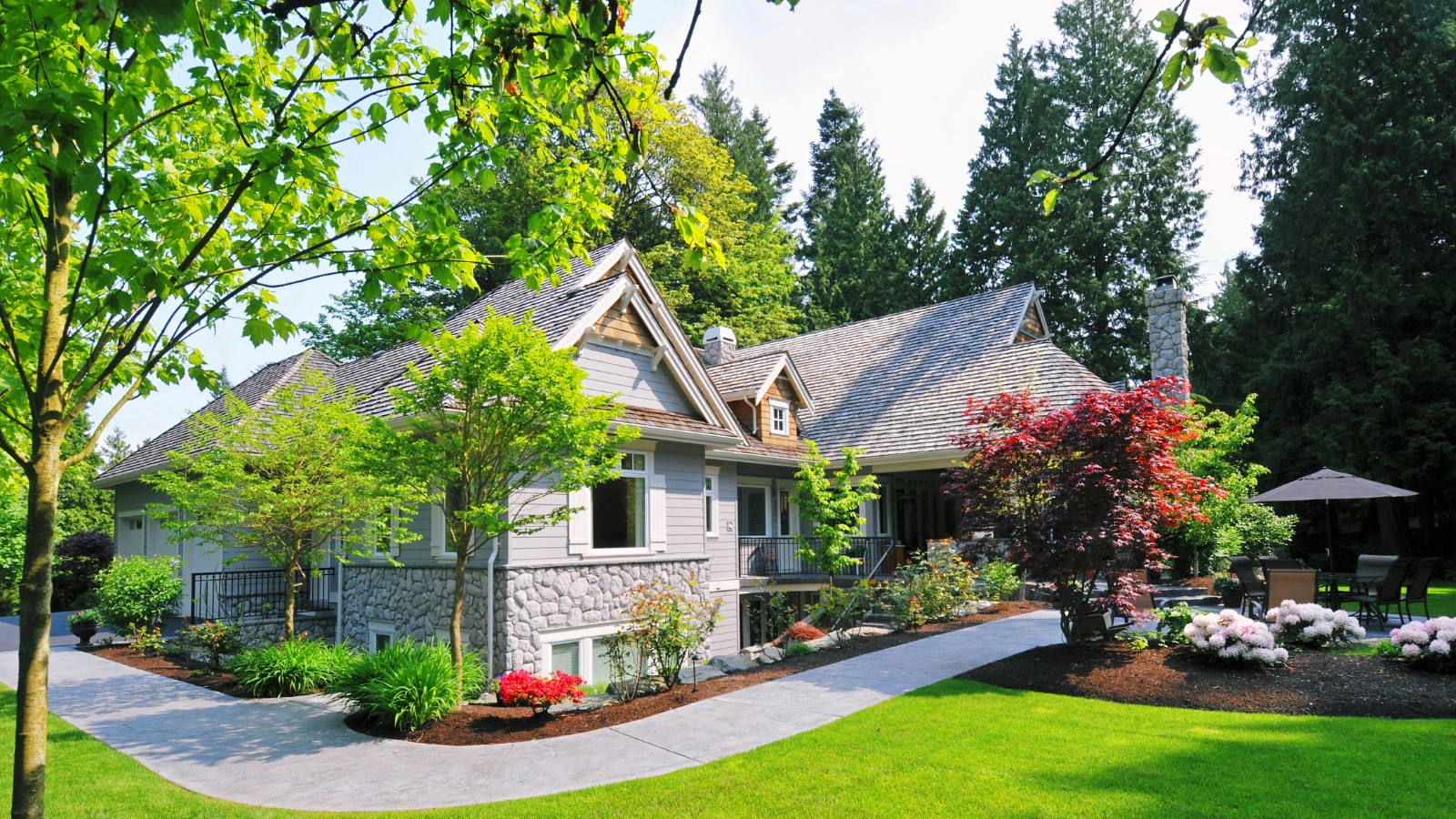 Beautiful home with manicured landscaping and concrete walkways, demonstrating the functional and aesthetic roles in hardscaping vs landscaping.