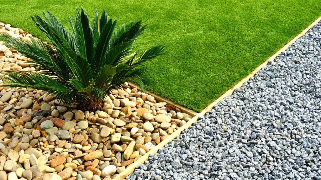 Example of hardscaping vs landscaping with defined zones of grass, decorative gravel, and stone beds featuring a tropical plant.