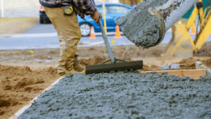 Construction worker leveling freshly poured concrete patio with excavator in South Austin neighborhood