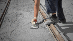 2.Worker smoothing freshly poured concrete for a driveway in South Austin construction project 